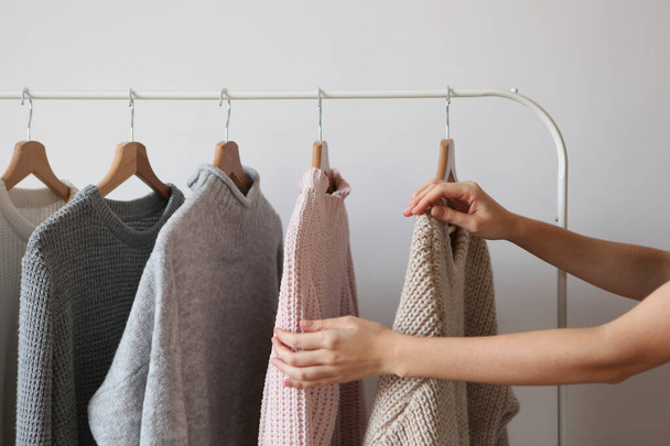 Девушка выбирает теплый свитер из гардероба вешалки
. - Фото, изображение