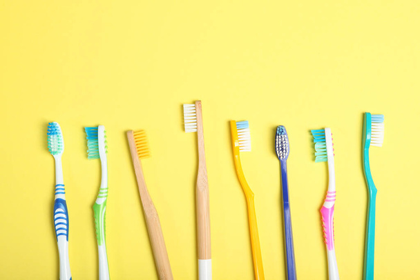 cepillos de dientes de bambú naturales y plástico en una vista superior de fondo de color
. - Foto, imagen