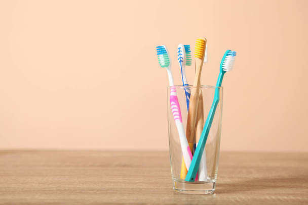 Φυσικό μπαμπού και πλαστικές οδοντόβουρτσες στο τραπέζι. - Φωτογραφία, εικόνα
