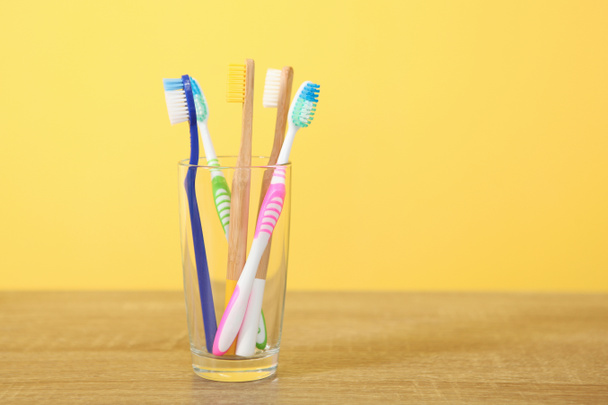 Φυσικό μπαμπού και πλαστικές οδοντόβουρτσες στο τραπέζι. - Φωτογραφία, εικόνα