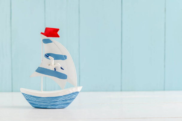 Sail boat Toy model with Seagull on white and blue wooden background - Nautical background - Fotografie, Obrázek