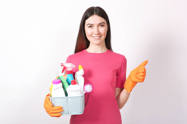 Une jeune femme au foyer tient dans ses mains des produits nettoyants sur un fond coloré
. - Photo, image