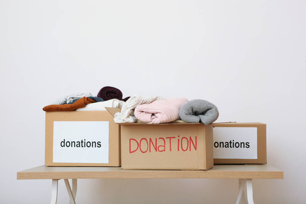 dozen met donaties met de nodige dingen op de tafel op een gekleurde achtergrond. Liefdadigheid, vrijwilligerswerk. - Foto, afbeelding