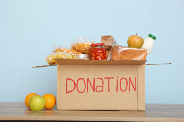 色のついた背景のテーブルの上に必要な物を寄付する箱です。慈善、ボランティア. - 写真・画像