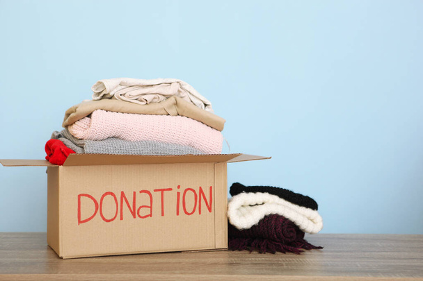 scatole con donazioni con le cose necessarie sul tavolo su uno sfondo colorato. Carità, volontariato
. - Foto, immagini