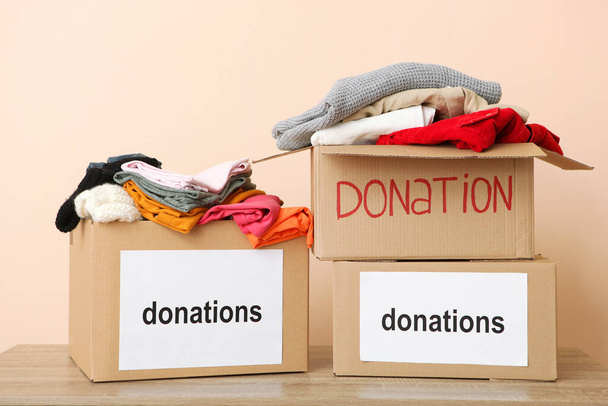 krabice s dary s potřebnými věcmi na stole na barevném pozadí. Charita, dobrovolnictví. - Fotografie, Obrázek