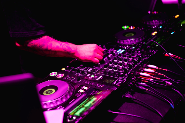 Dj hands on equipment deck and mixer with turntable dj in the nightclub at party - Photo, Image
