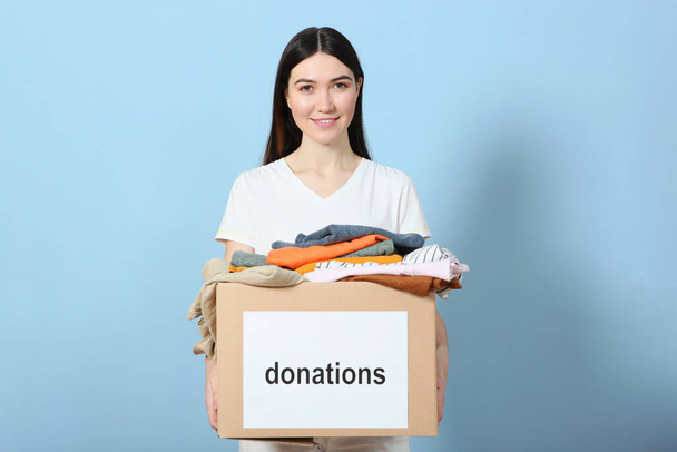 Menina com uma caixa de doações em um fundo colorido. lugar para texto. Doações, voluntariado
. - Foto, Imagem