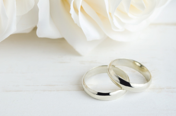 白いバラとヴィンテージ木製のテーブルの上に結婚指輪の閉鎖 - 写真・画像