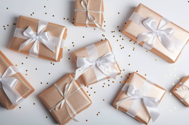 Gifts in golden packaging on a light background with a place for text top view. birthday, christmas, new year, mother's day, march 8, valentines day - Φωτογραφία, εικόνα
