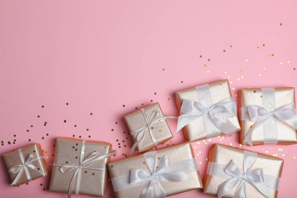 Geschenke in Goldverpackung auf farbigem Hintergrund mit Platz für Text von oben. Geburtstag, Weihnachten, Neujahr, Muttertag, 8. März, Valentinstag - Foto, Bild