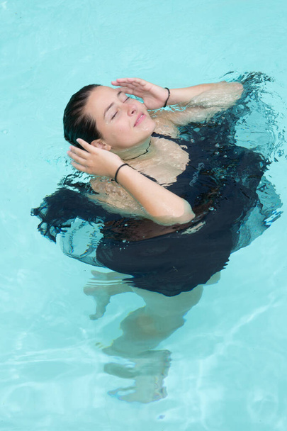 hermosa mujer joven en vestido negro chica nadando en la piscina
 - Foto, imagen