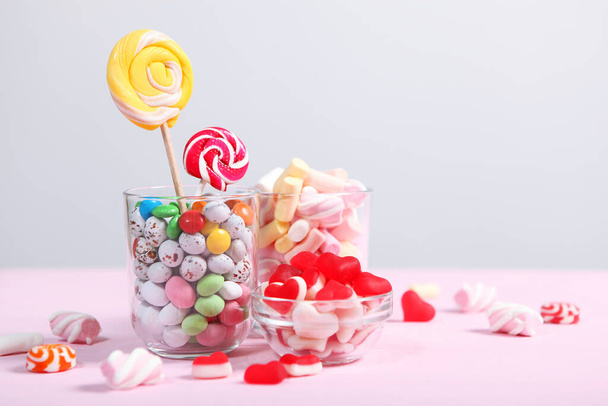 verschiedene Süßigkeiten und Süßigkeiten auf dem Tisch auf farbigem Hintergrund. - Foto, Bild