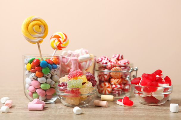 Masanın üzerinde renkli bir arkaplanda çeşitli şekerler ve tatlılar var.. - Fotoğraf, Görsel
