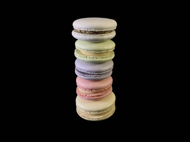 Multicolored tasty macarons on a black background. Colorful french macarons of various tastes, top view. Original dessert, a stack of homemade cookies. - Фото, зображення