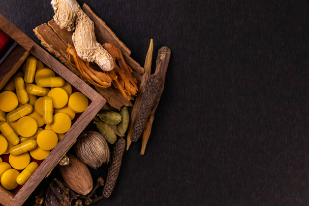 Assorted different spices and ayurvedic medicine in a wooden box on black background with copy space. Herbal concept - Foto, Bild