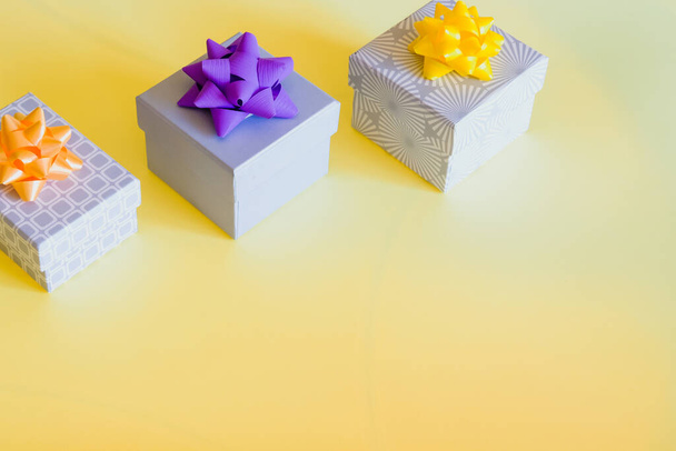 Güneşli sarı arka planda renkli hediye kutuları ve fiyonklar. Mutlu bayramlar tasarımı.  - Fotoğraf, Görsel