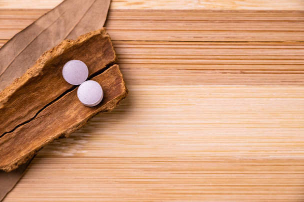 Draufsicht auf zwei weiße ayurvedische Arzneimittel mit Zimtstange und Lorbeerblatt auf Holzgrund. Ayurveda-Konzept - Foto, Bild