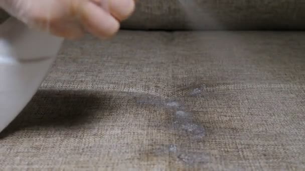 Cleaning furniture surface with wet wipe and spray. Disinfecting sofa fabric at home, apartment or office. with liquid cleaner and wipe. Housewife cleaning house for good family healthcare. 4 k video - Filmmaterial, Video