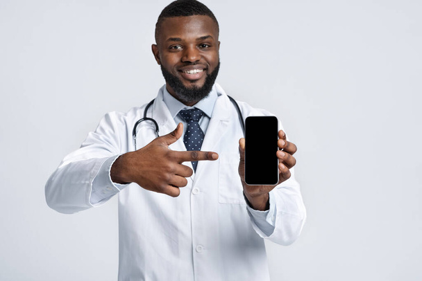 Joyeux thérapeute noir pointant vers smartphone vide
 - Photo, image
