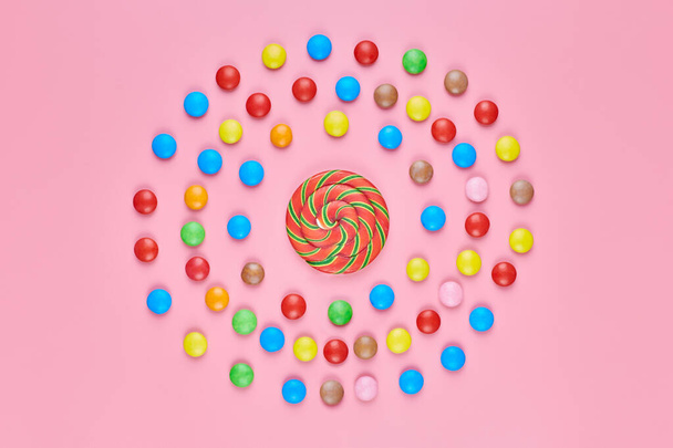 Sladké lízátko a sladkosti na růžovém pozadí, kopírovat prostor. Love to colorful sweetmeat in childhood concept - Fotografie, Obrázek