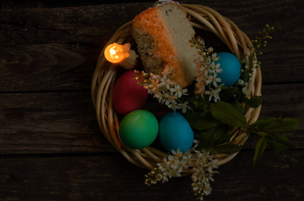 Cena di Pasqua, uova di pollo colorate e fiamma di candela su un vecchio tavolo di legno la sera
 - Foto, immagini