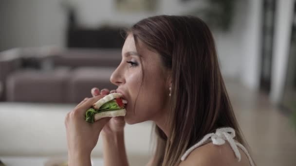 Krásná dáma těší sendvič během oběda v pokoji - Záběry, video