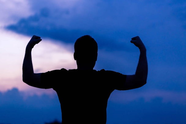 Silhouette of a man with hands raised in the sunset, empowered concept. - Photo, Image