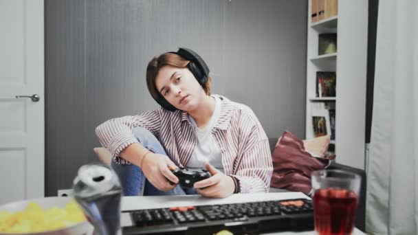 Nudna młoda dziewczyna gracz gra w gry wideo na konsoli z bezprzewodowym kontrolerem - Materiał filmowy, wideo