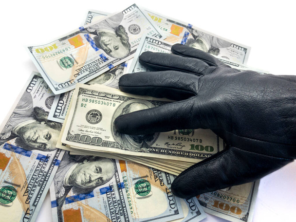 Αμερικάνικα δολάρια και χέρι. Για να κλέψει χρήματα. Σύνθεση χάρτινου χρήματος και χεριών. Κλέφτης. Ρομπ. Επιχειρήσεις και οικονομικά. Δολάρια και ένα χέρι σε ένα μαύρο γάντι. - Φωτογραφία, εικόνα