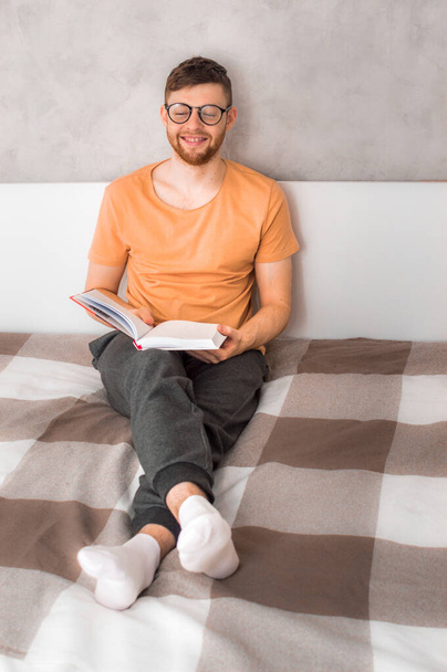 Young man smiling with a book in his hands. Vertical photo - Photo, image