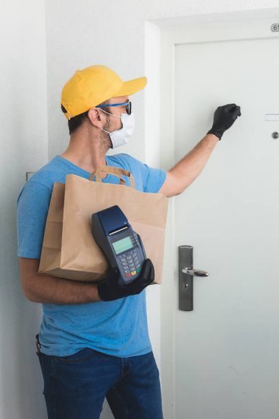 Delivery guy with protective mask holding box / bag with groceries and POS for contactless payment. - Photo, Image