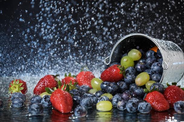 Salada de frutas fechar em balde de metal caindo. Cocktail multivitamínico de morango, uva, mirtilo. Estilo de vida saudável. Dieta de verão. Conjunto de frutas sob as gotas de água
. - Foto, Imagem