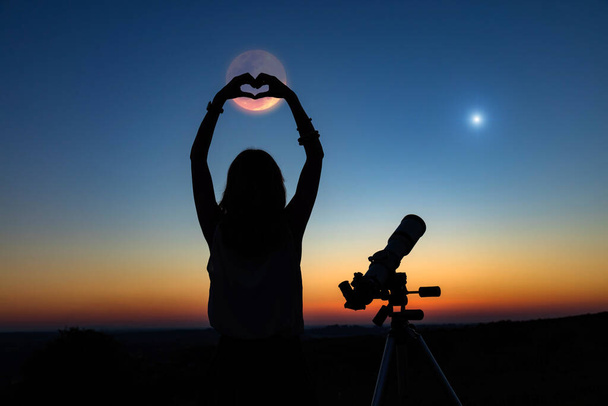 Silhouette einer Frau und Teleskop mit Dämmerungshimmel. - Foto, Bild