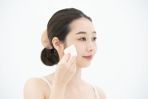 Asiatique (japonais) jeune femme mettre bouffée à sa peau faciale
 - Photo, image