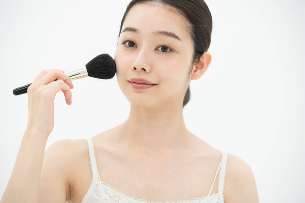 Asiatique (japonais) jeune femme appliquant maquillage avec un pinceau doux
 - Photo, image