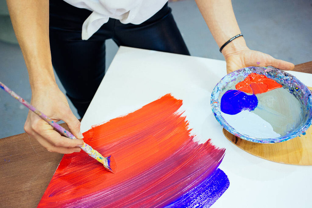 画家は新しい絵を描き、赤と青の油絵具を使用しています。赤と青のパレット. - 写真・画像