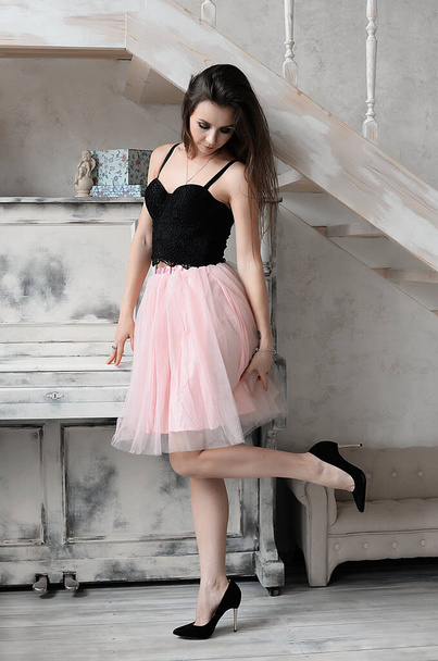a cute girl with professional makeup in a beautiful interior in denim shorts and a tulle skirt and a lace bodysuit smiles and has a great time - 写真・画像