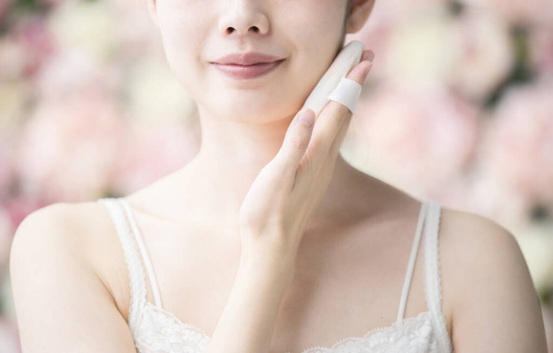 アジア系の若い女性が顔の皮膚にパフをかける - 写真・画像