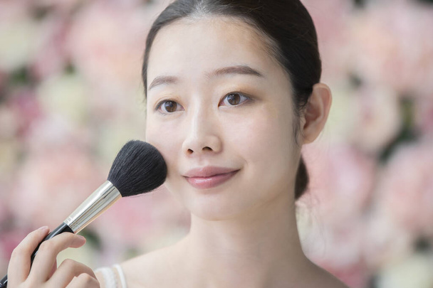 Asiatique (japonais) jeune femme appliquant maquillage avec un pinceau doux
 - Photo, image