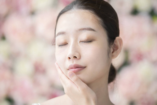 Een Aziatische (Japanse) jonge vrouw die haar huidconditie aanraakt en controleert - Foto, afbeelding