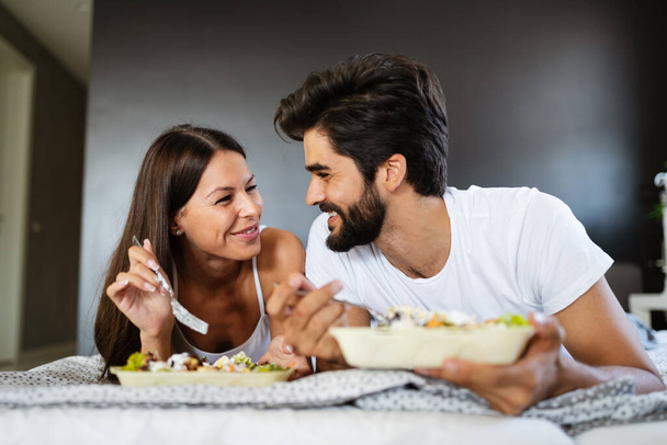 Happy young couple in love having breakfast in bed - 写真・画像