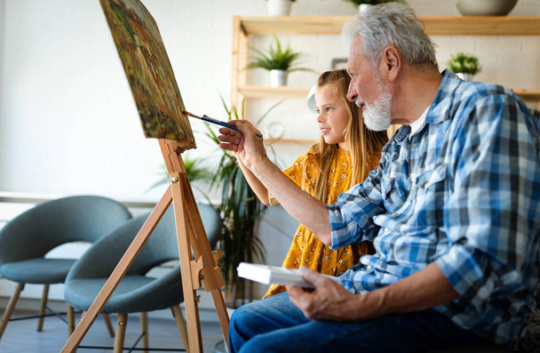 Senior man and his grandchild drawing, painting together. Happy family time - Photo, Image