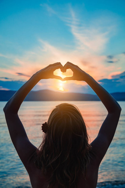 Žena se srdcem ve tvaru znamení těší oceánu tropického času. - Fotografie, Obrázek