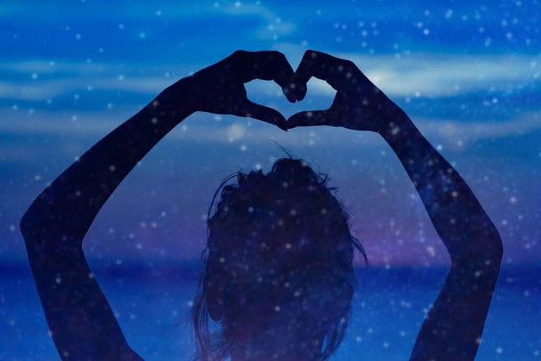 Silhouette di una ragazza che tiene il simbolo a forma di cuore per amore su un cielo stellato notturno
.  - Foto, immagini