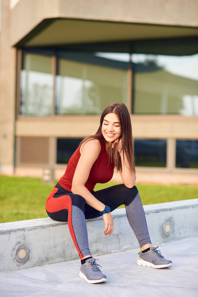 Mujer deportiva haciendo una pausa después de hacer ejercicio al aire libre
. - Foto, imagen