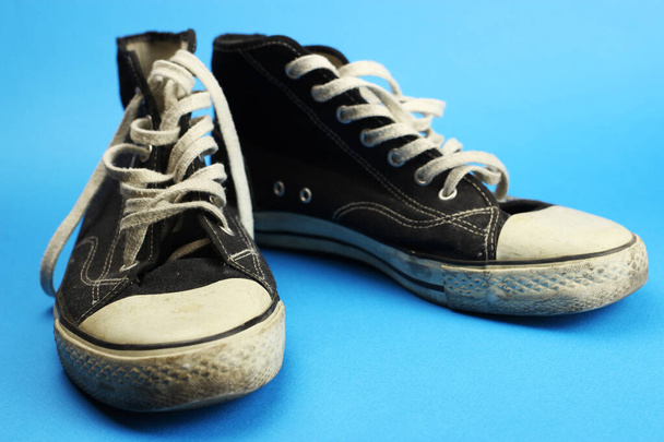 scarpe da ginnastica nere vecchie, indossate, vintage su sfondo blu
 - Foto, immagini