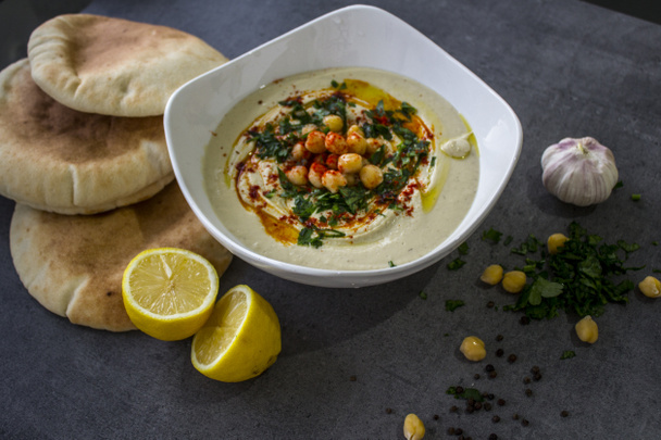 Plate of fresh homemade hummus with pita bread on the table. Authentic food of Middle East. Healthy eating concept. Vegan balanced dish. Traditionalmeal of Israel. - Фото, зображення