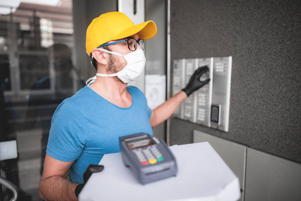 Deliveryman with protective medical mask holding pizza box - days of viruses and pandemic, food delivery to your home. - Photo, Image