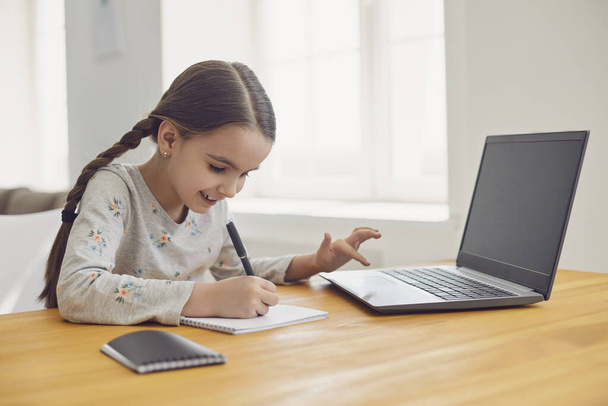 Online vzdělávání dětí. Dívka školačka se učí lekci on-line pomocí notebooku videa, zatímco sedí na chatu doma. - Fotografie, Obrázek